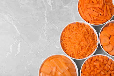 Flat lay composition with bowls of differently cut carrots on marble background. Space for textの写真素材