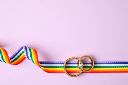 Top view of wedding rings and rainbow ribbon on color background, space for text. gay symbolの写真素材