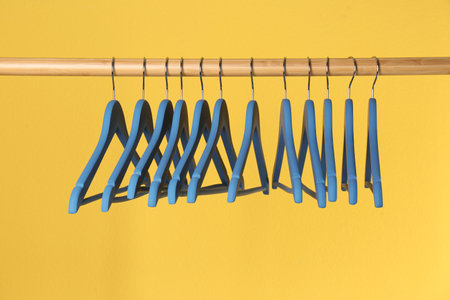 Wooden rack with clothes hangers on color backgroundの写真素材