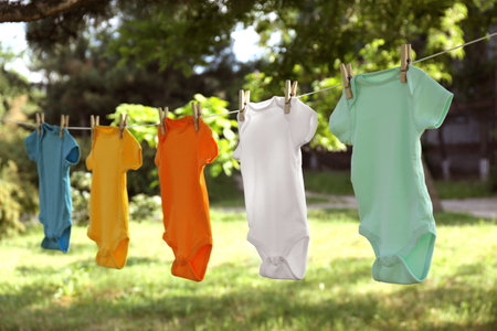 Colorful baby clothes hanging on clothes line outsideの写真素材
