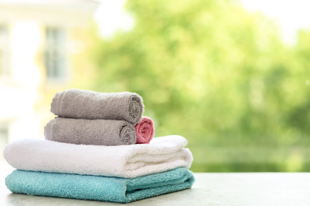 Stack of clean towels on table against blurred background. Space for textの写真素材