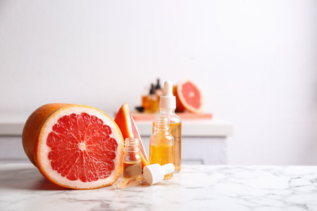 Bottles of essential oil and grapefruit slices on table. Space for textの写真素材