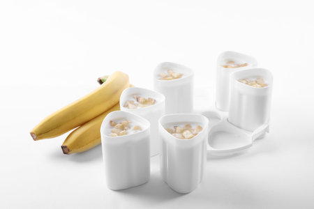 Cups of yogurt with bananas on white background. Multi-cooker recipeの写真素材