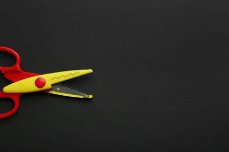 Decorative edge scissors on dark background, top view. Space for textの写真素材