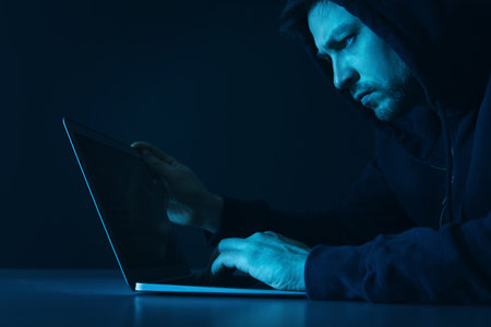 Man using laptop in dark room. criminal offenseの写真素材