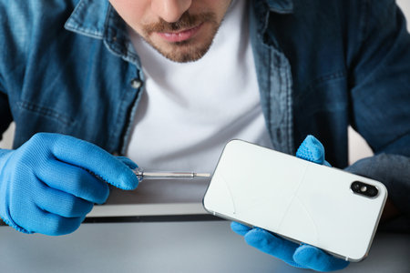 Technician repairing broken smartphone at table, closeupの写真素材