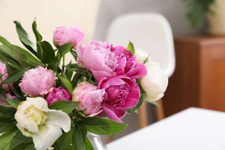 Bouquet of beautiful peonies on table in room, closeup. Space for textの写真素材