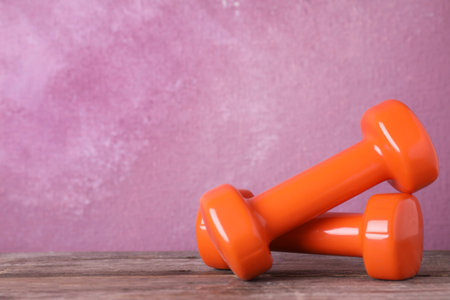 Stylish dumbbells on table against color background, space for text. home fitnessの写真素材