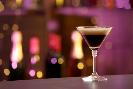 Glass of Espresso Martini on counter in bar, space for text. alcohol cocktail