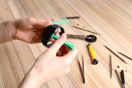 Technician fixing broken smart watch at table, closeup. repair service