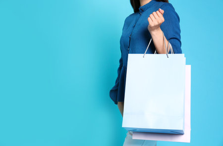 Woman with blank paper bags against color background, closeup. Space for textの写真素材