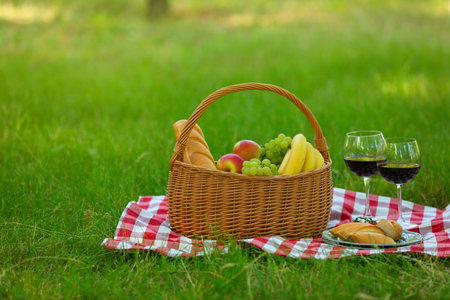 Wicker basket with food and wine on blanket in park, space for text. summer picnicの写真素材