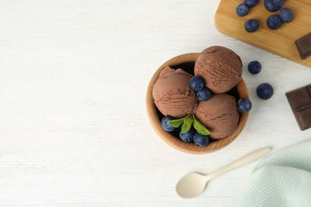 Flat lay composition with bowl of chocolate ice cream and blueberries on white wooden table, space for textの写真素材