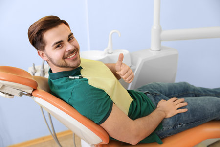 Happy patient on dentist's chair in modern clinic, space for textの写真素材