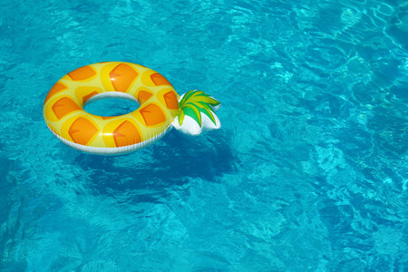 Bright inflatable pineapple ring floating in swimming pool on sunny day. Space for textの写真素材