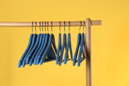 Wooden rack with clothes hangers on color backgroundの写真素材