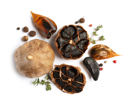 Aged black garlic with thyme and peppercorns on white background, view from aboveの写真素材