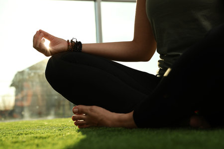 Young woman practicing yoga in sunlit room, closeupの写真素材