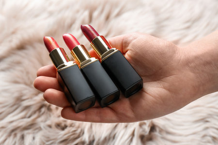 Woman holding different lipsticks over furry fabric, closeup. professional makeup productsの写真素材