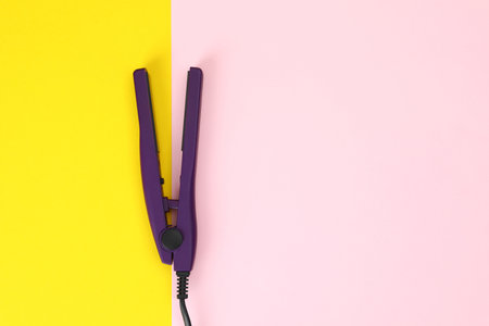 Modern hair iron for straightening on color background, top view with space for textの写真素材