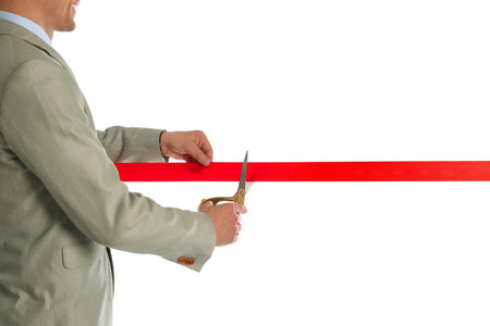 Man in office suit cutting red ribbon isolated on white, closeupの写真素材