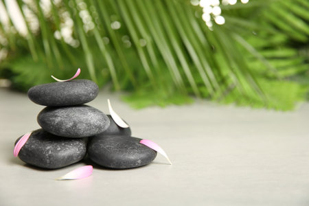 Spa stones with petals on table against blurred background. Space for textの写真素材