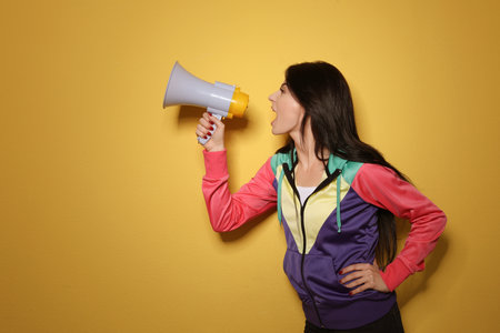 Portrait of emotional woman using megaphone on color background. Space for textの写真素材