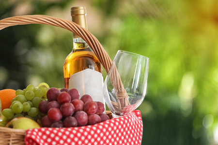 Picnic basket with products and wine on blurred background, space for textの写真素材