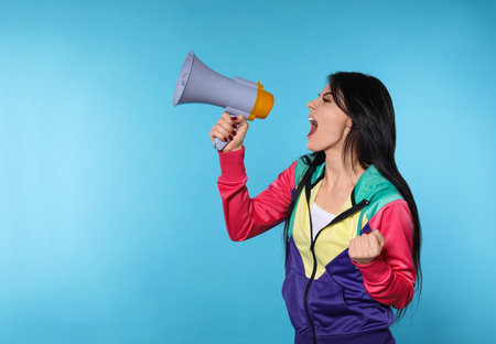 Portrait of emotional woman using megaphone on color background. Space for textの写真素材