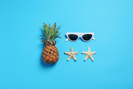 Sunglasses, pineapple and starfishes on color background, flat lay. beach accessoriesの写真素材