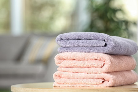 Stack of folded clean soft towels on table indoors. Space for textの写真素材