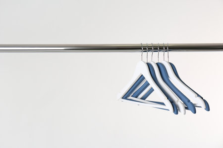 Metal rack with clothes hangers on white background, space for textの写真素材
