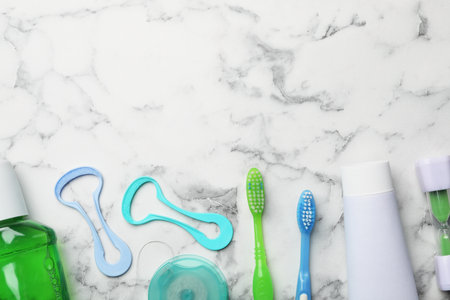 Flat lay composition with tongue cleaners and teeth care products on marble background. Space for...