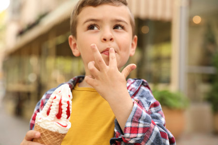 Adorable little boy with delicious ice cream outdoorsの写真素材