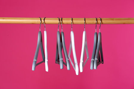 Wooden rack with clothes hangers on color backgroundの写真素材