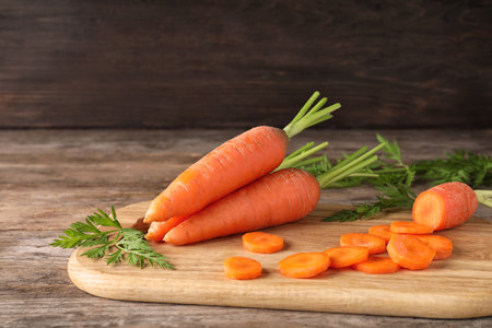 Board with cut carrot on wooden backgroundの写真素材