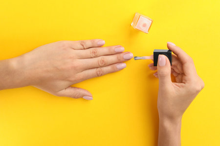 Woman applying nail polish on color background, above viewの写真素材