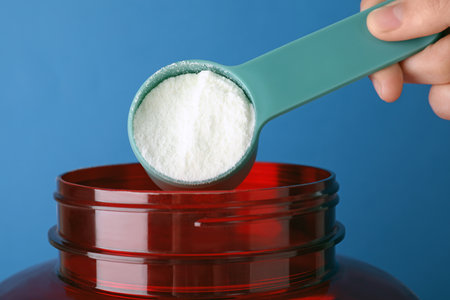 Man taking protein powder with scoop from jar against color background, closeupの写真素材