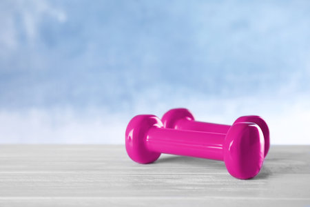 Stylish dumbbells on table against color background, space for text. fitness equipmentの写真素材