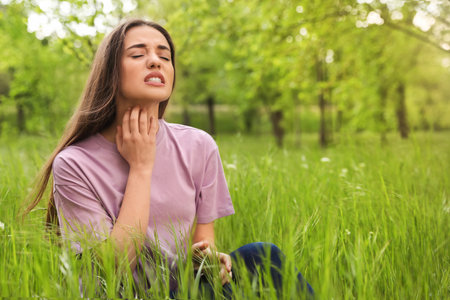 Young woman scratching neck outdoors, space for text. seasonal allergy