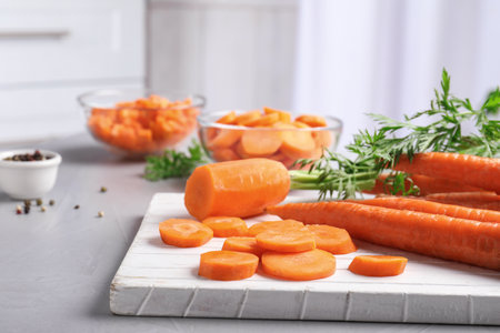 Board with slices of carrot on tableの写真素材