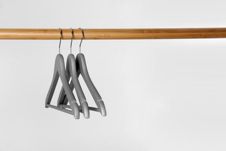 Wooden rack with clothes hangers on white background, space for textの写真素材