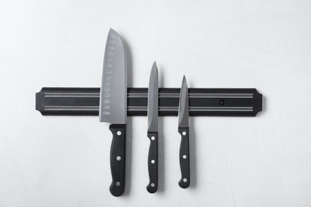 Magnetic holder with set of knives on gray stone backgroundの写真素材