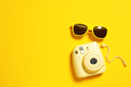 Sunglasses and camera on color background, top view with space for text. beach accessoriesの写真素材