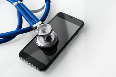 Smartphone and stethoscope on light table, closeup with space for text. Repair serviceの写真素材