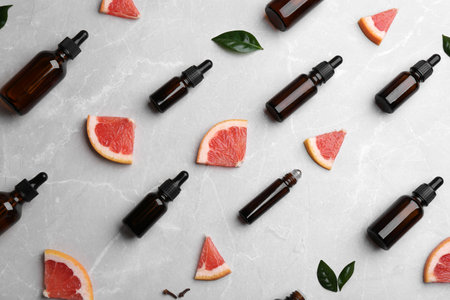 Flat lay composition with grapefruit slices and bottles of essential oil on gray backgroundの写真素材