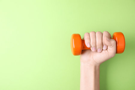 Woman holding vinyl dumbbell on color background, closeup with space for textの写真素材