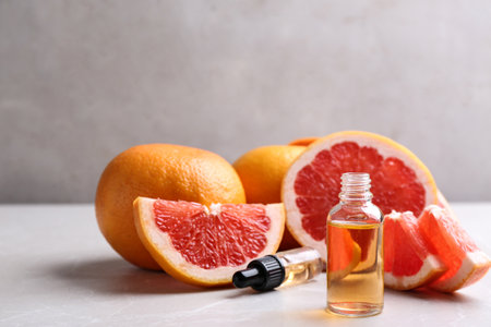 Bottle of essential oil and grapefruits on gray table, space for textの写真素材