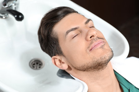 Man at sink ready for hair washing in beauty salonの写真素材