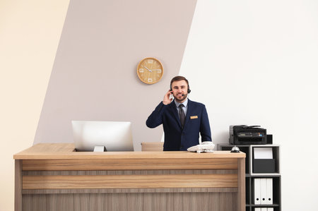 Portrait of receptionist working at desk in modern hotelの写真素材